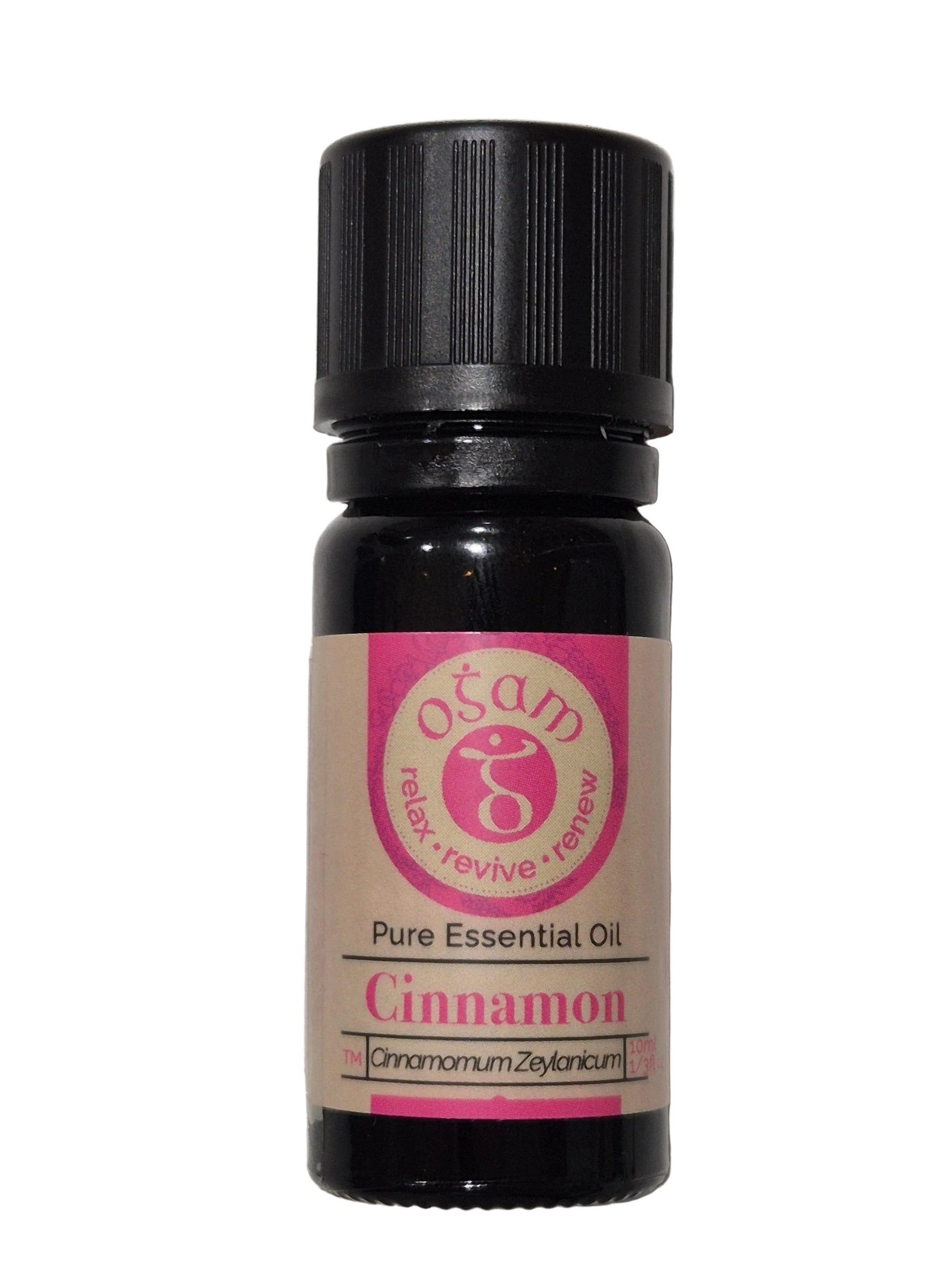 A small essential oil bottle labeled 'Ocean Organic Cinnamon Pure Essential Oil' with a black cap and a pink and beige label, resting on a textured white surface.